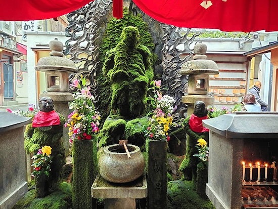 Mossy green statue of Fudo Myoo at Hozenji Temple, covered from years of water splashes