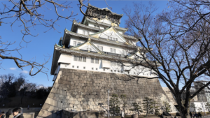 Majestic Osaka Castle with green roofs and stone walls against the city skyline